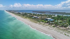 Vista aérea de una zona costera con playa, casas y aguas turquesas cristalinas.