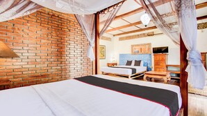 A room with a brick wall, a bed with a canopy, a wooden nightstand, and a television. - Hotel O Prawirotaman Near Keraton Yogyakarta Formerly Chez Laelik Guesthouse (Yogyakarta)