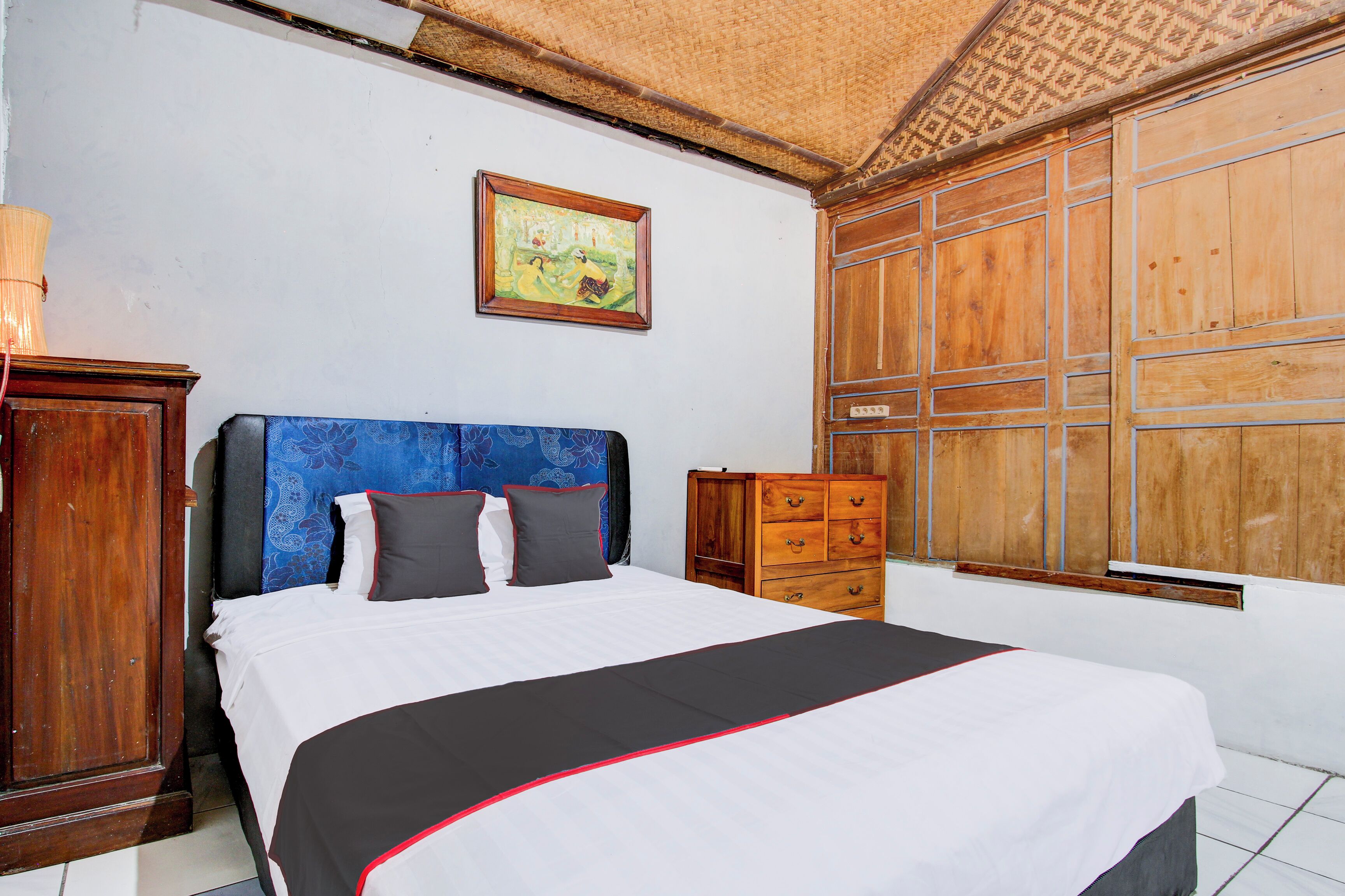 A bedroom with a bed, wooden wardrobe, and a window with wooden shutters.