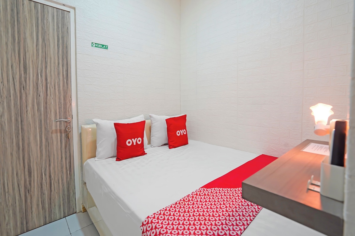 Une chambre d’hôtel avec un lit, une porte en bois et un mur en briques blanches.