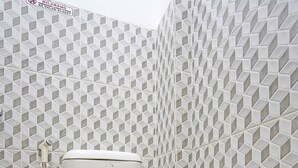 Une salle de bain avec des toilettes, une douche et un carrelage au sol.