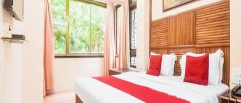 Una habitación de hotel con una cama grande, cabecera de madera, un cuadro sobre la cama y una ventana con cortinas.