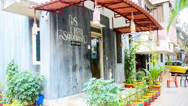 A hotel entrance with a sign reading "Hotel Subhash" and a series of potted plants lining the steps. - Hotel Subhash (Mumbai)