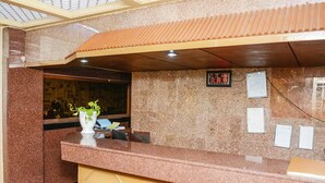 A reception area with a marble counter, a clock, and a plant. - Hotel Subhash (Mumbai)