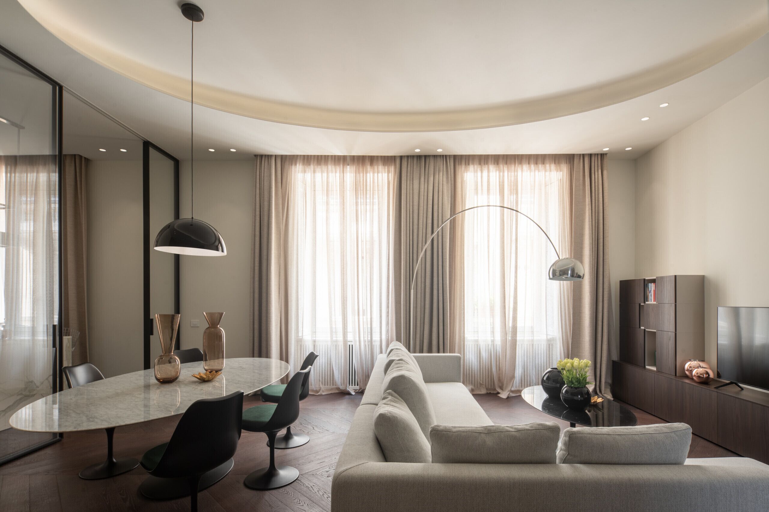 A modern living room with a round dining table, a sofa, and a TV.