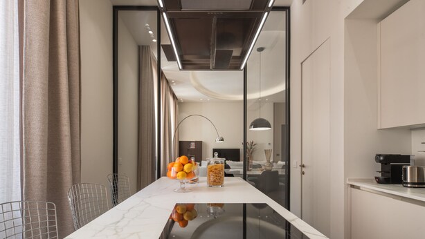 A modern kitchen with a marble countertop, a coffee machine, and a glass cabinet with food items. - Sant'Ambrogio Luxury Apartment R&R (Milano)