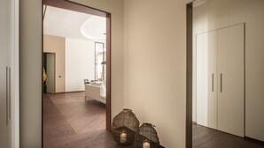 A hallway with wooden flooring, a white door, and two lit candles in woven baskets. - Sant'Ambrogio Luxury Apartment R&R (Milano)