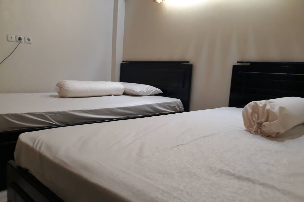 Een hotelkamer met twee bedden, elk met een zwart hoofdeinde en witte beddengoed.