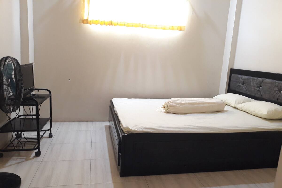 Een slaapkamer met een bed, een bureau en een stoel.