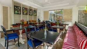 A dining area with tables and chairs, a bench, and a ceiling fan. - The Kanjeng Suites Petitenget (Keroboken Kelod)