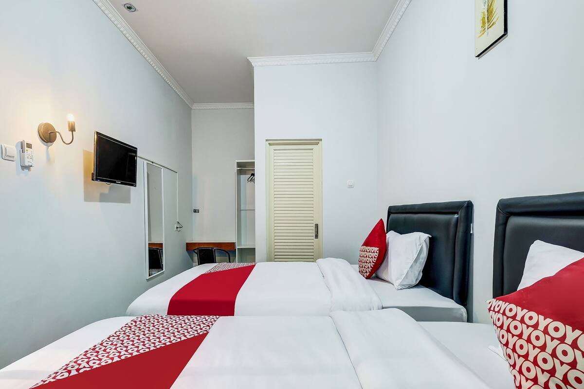 Hotellihuone, jossa on kaksi sänkyä, televisio, peili ja vaatekaappi.