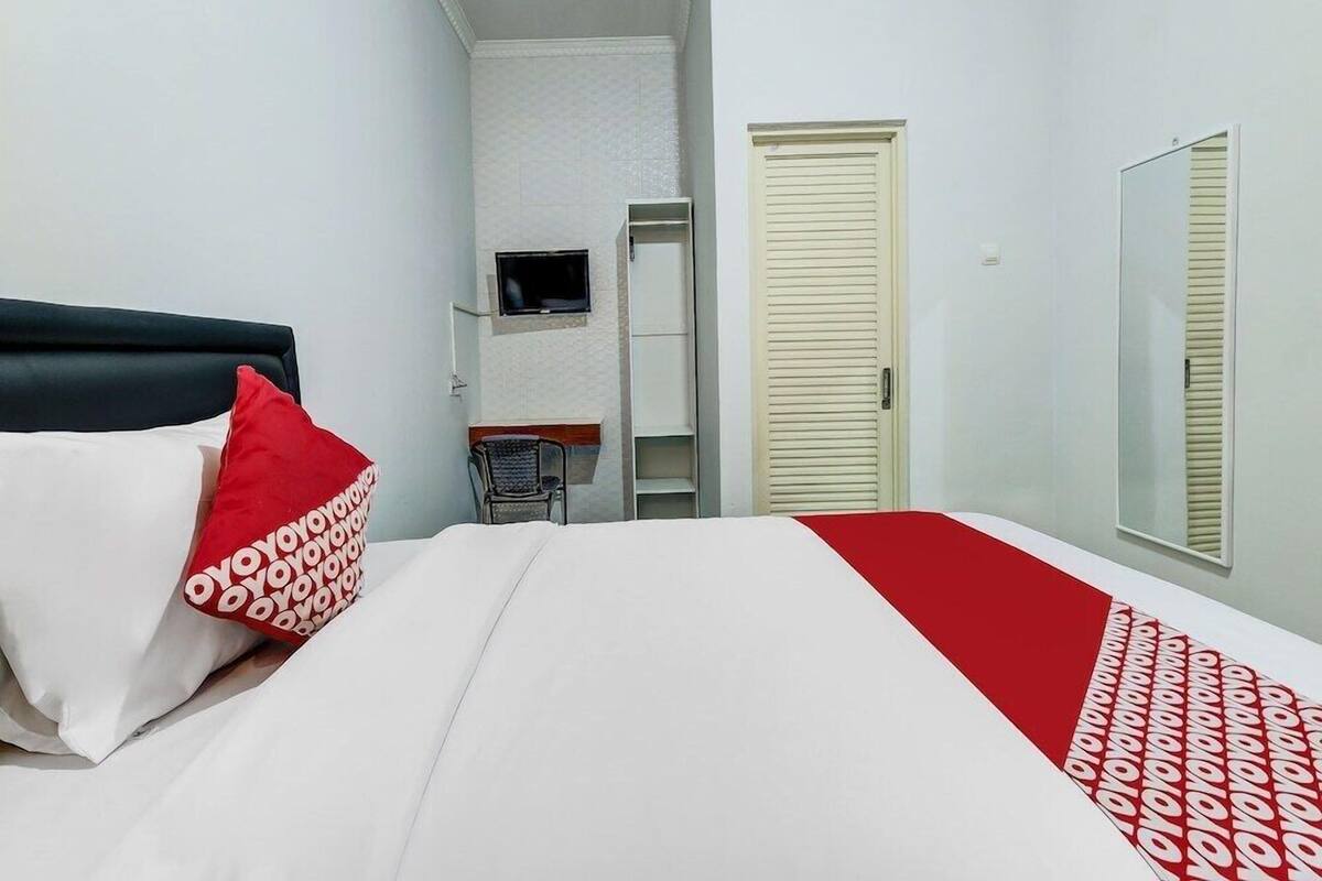 Hotellihuone, jossa on sänky, televisio, vaatekaappi ja ovi.