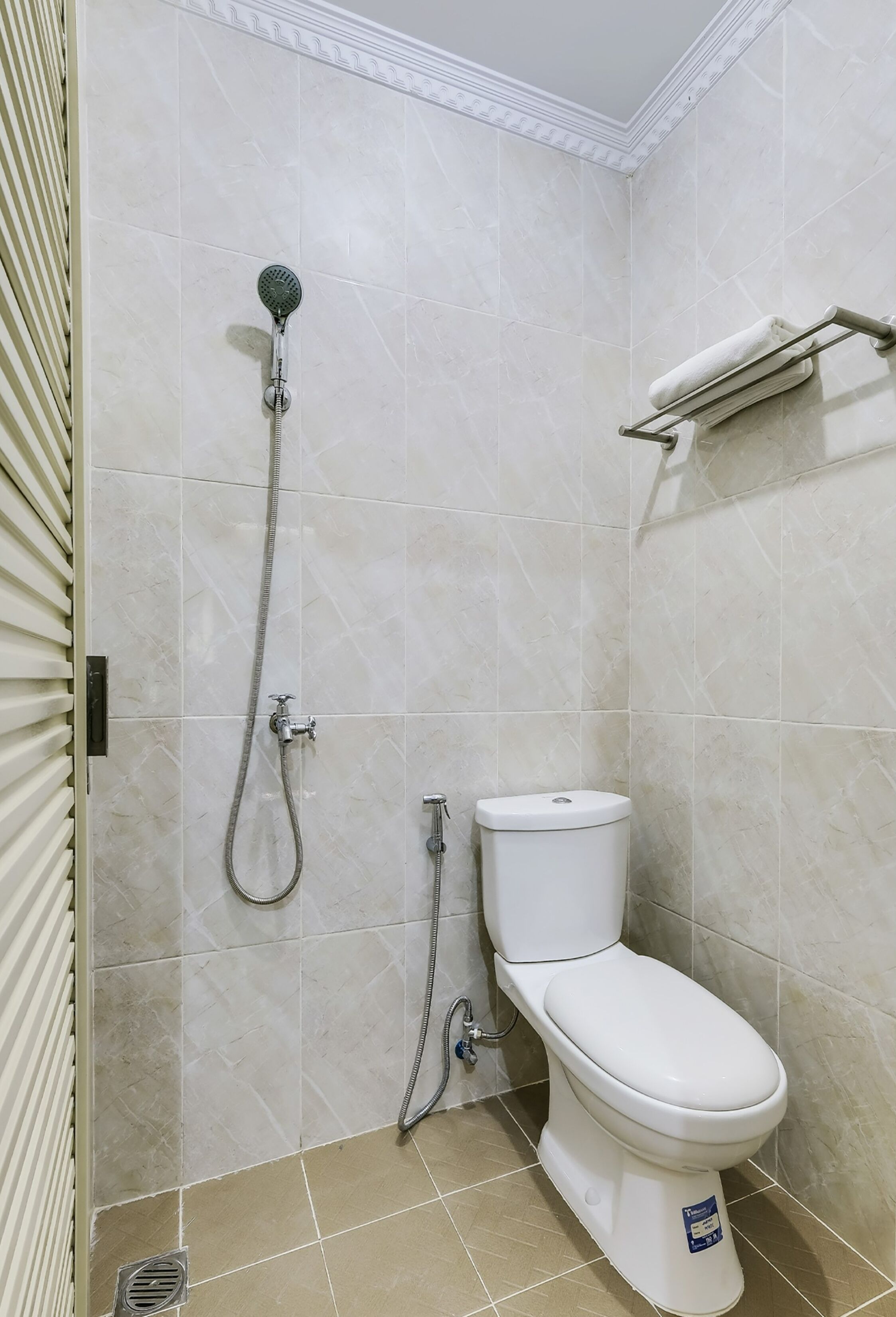 A bathroom with a shower, toilet, and a towel rack.