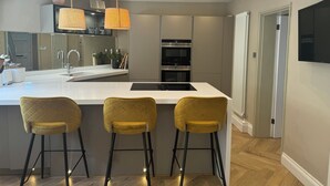 A modern kitchen with a central island, bar stools, and built-in appliances.