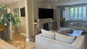 A spacious living room with a fireplace, a television mounted above it, and a comfortable seating area with a sofa and a coffee table.