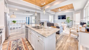 A spacious kitchen with a large island, wooden ceiling, and modern lighting fixtures. - Beachfront |Cargo Elevator | Steps to Beach | Baby+Beach Gear | Lawn+Board Games (Long Beach)
