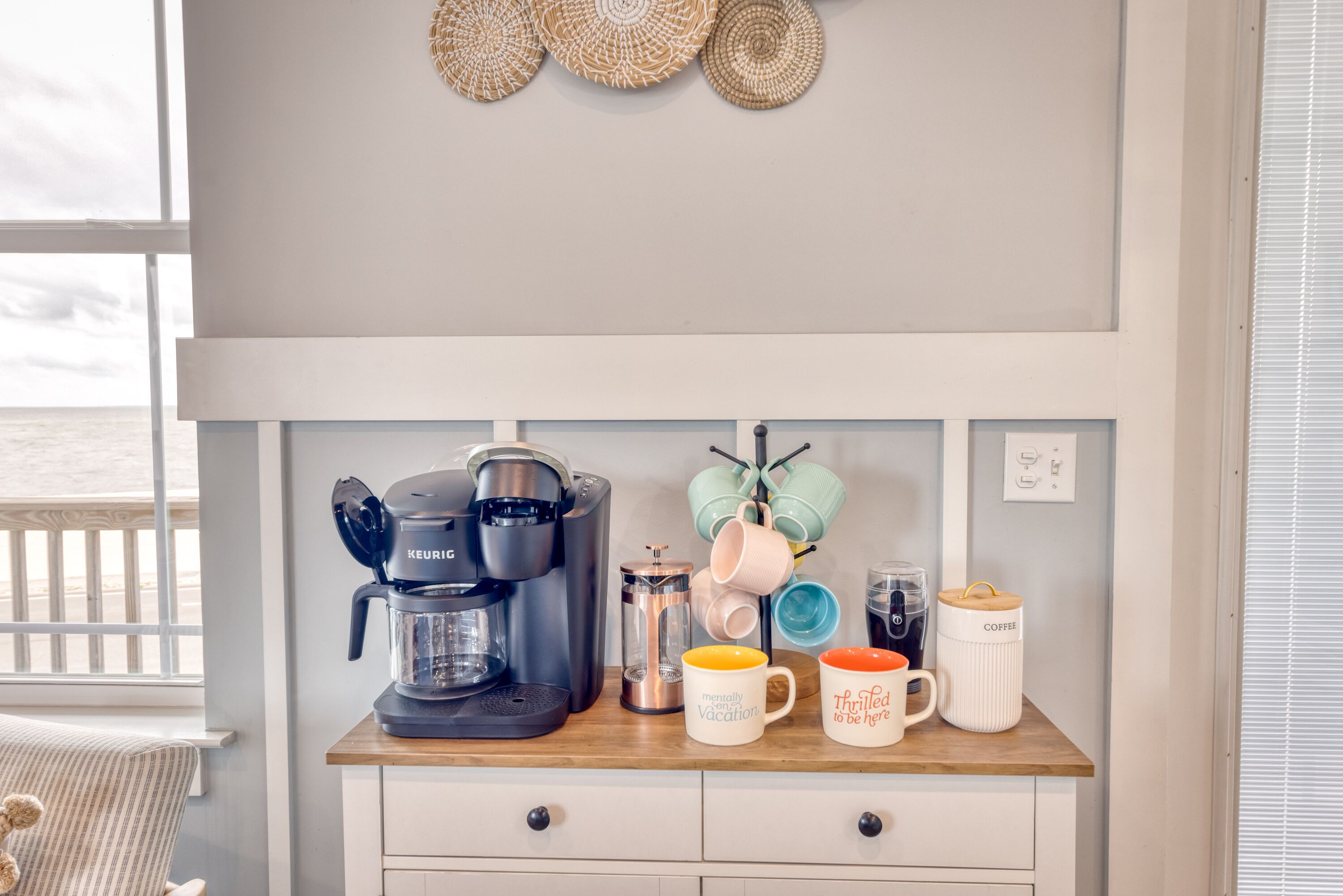 Eine Küchenarbeitsplatte mit einer Keurig-Kaffeemaschine, einem French-Press-Kaffeebereiter und verschiedenen Tassen.