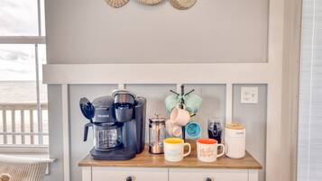 Eine Küchenarbeitsplatte mit einer Keurig-Kaffeemaschine, einem French-Press-Kaffeebereiter und verschiedenen Tassen.