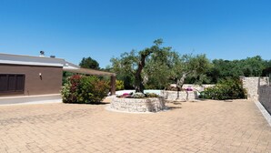 Un patio con un muro de piedra, una pérgola y un edificio de fachada marrón.