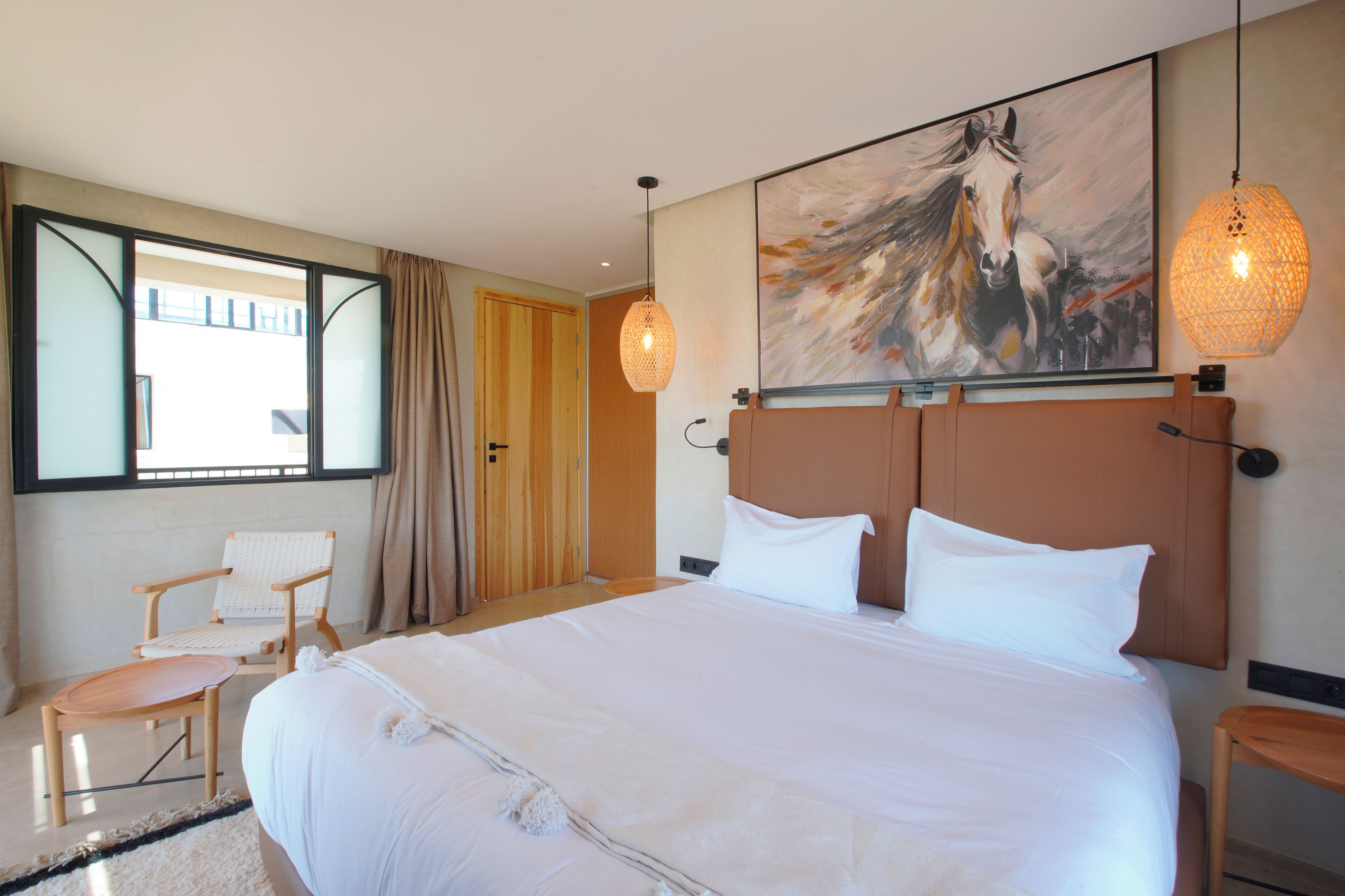 Une chambre d’hôtel avec un grand lit, une chaise, un tableau et une fenêtre.