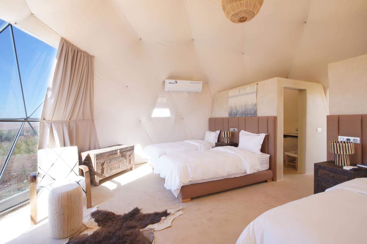 Ein geräumiges Schlafzimmer mit zwei Betten, einem großen Fenster und Blick ins Freie.
