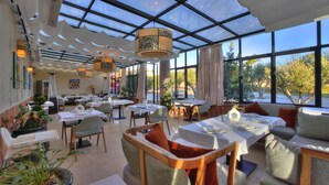 A restaurant with a glass ceiling, tables set for dining, and potted plants.