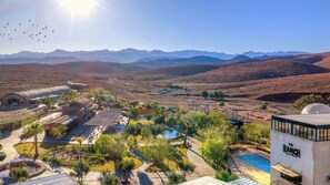 A resort with a pool, outdoor seating, and a view of mountains.