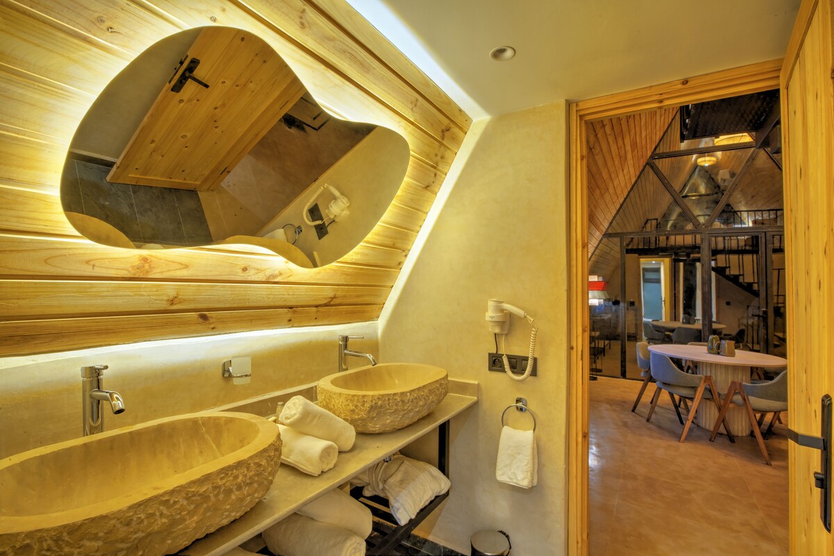 A modern bathroom with a large skylight, two stone sinks, and a mirror.