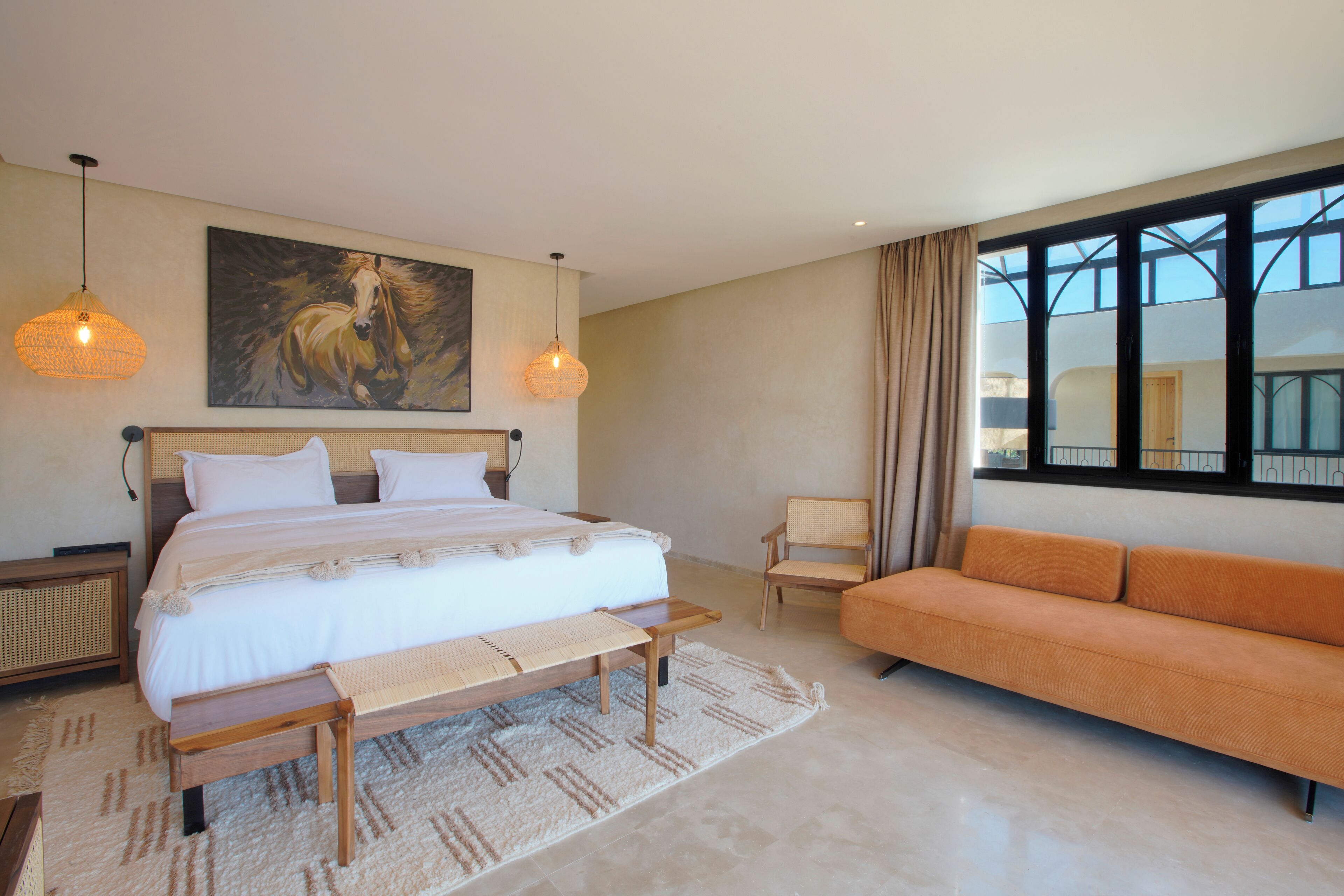 A bedroom with a large bed, a sofa, a chair, and a painting on the wall.