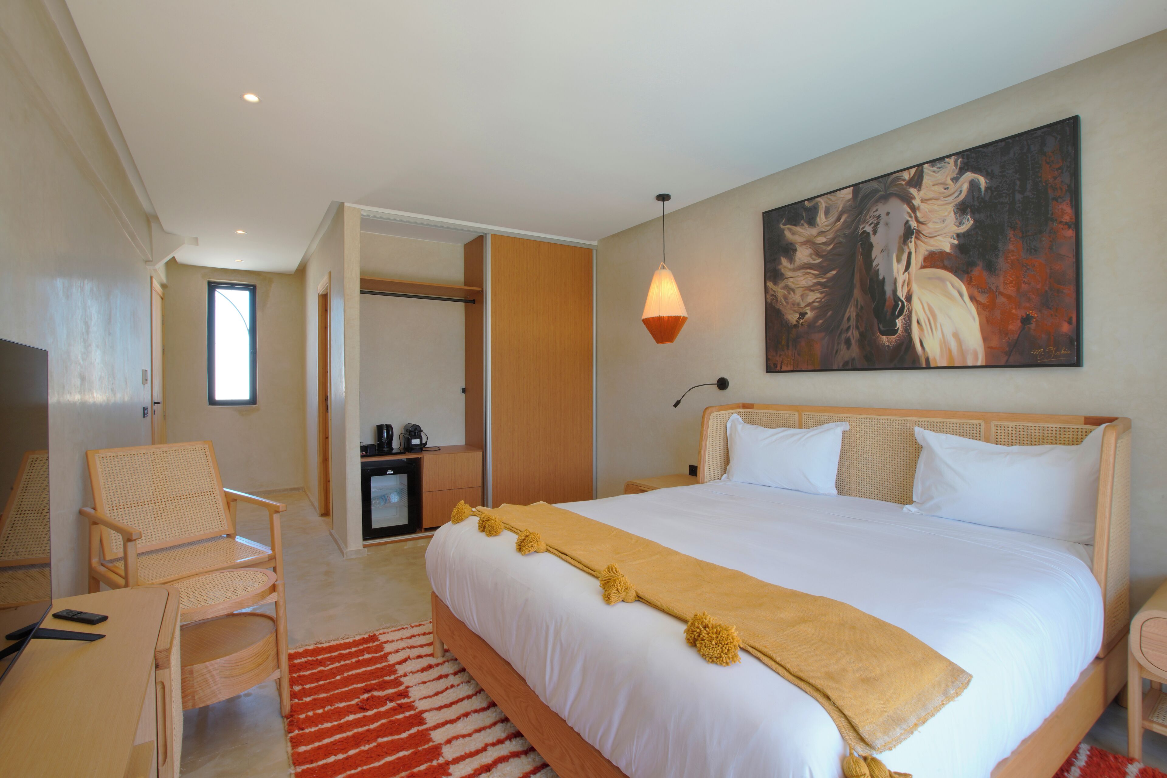 Um quarto espaçoso com uma cama grande, uma cabeceira de madeira, um quadro na parede e um tapete vermelho.