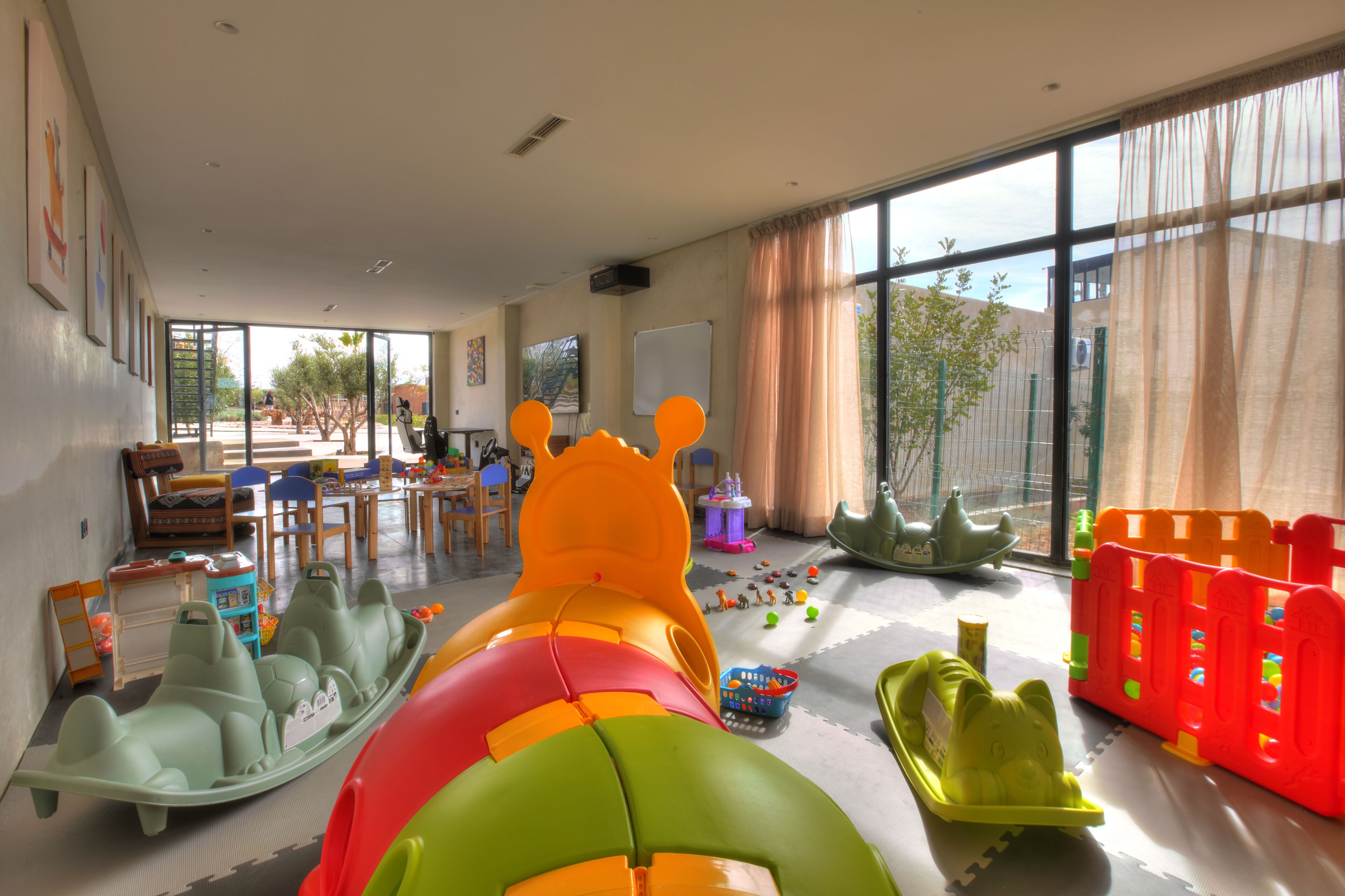 A spacious room with large windows, a play area with colorful toys, and a view of the outside.