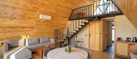 A modern interior with a wooden ceiling, a staircase, a round dining table, and a sofa.