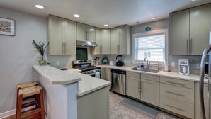 Una cocina moderna con armarios verde claro, electrodomésticos de acero inoxidable y una isla central.