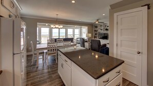 A modern kitchen with white cabinets, a granite countertop, and a dining area with a table and chairs.