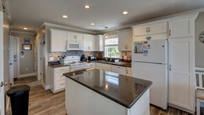 A modern kitchen with white cabinets, a central island, and a stainless steel refrigerator.