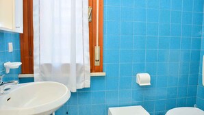 A bathroom with a sink, toilet, and shower curtain. - Holiday apartment mit Terrasse (Bibione)