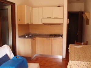 A compact kitchen with wooden cabinets, a sink, and a stove.
