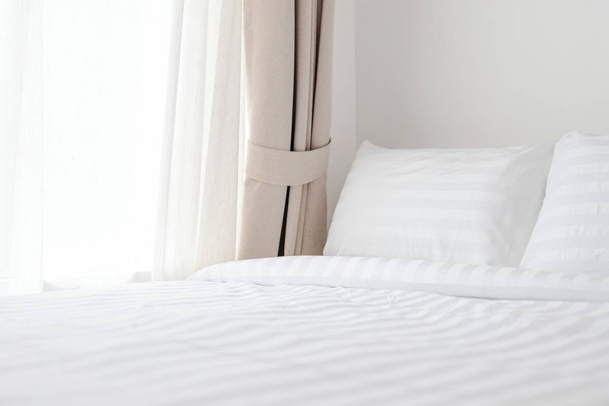 A neatly made bed with white linens and a simple, clean design.