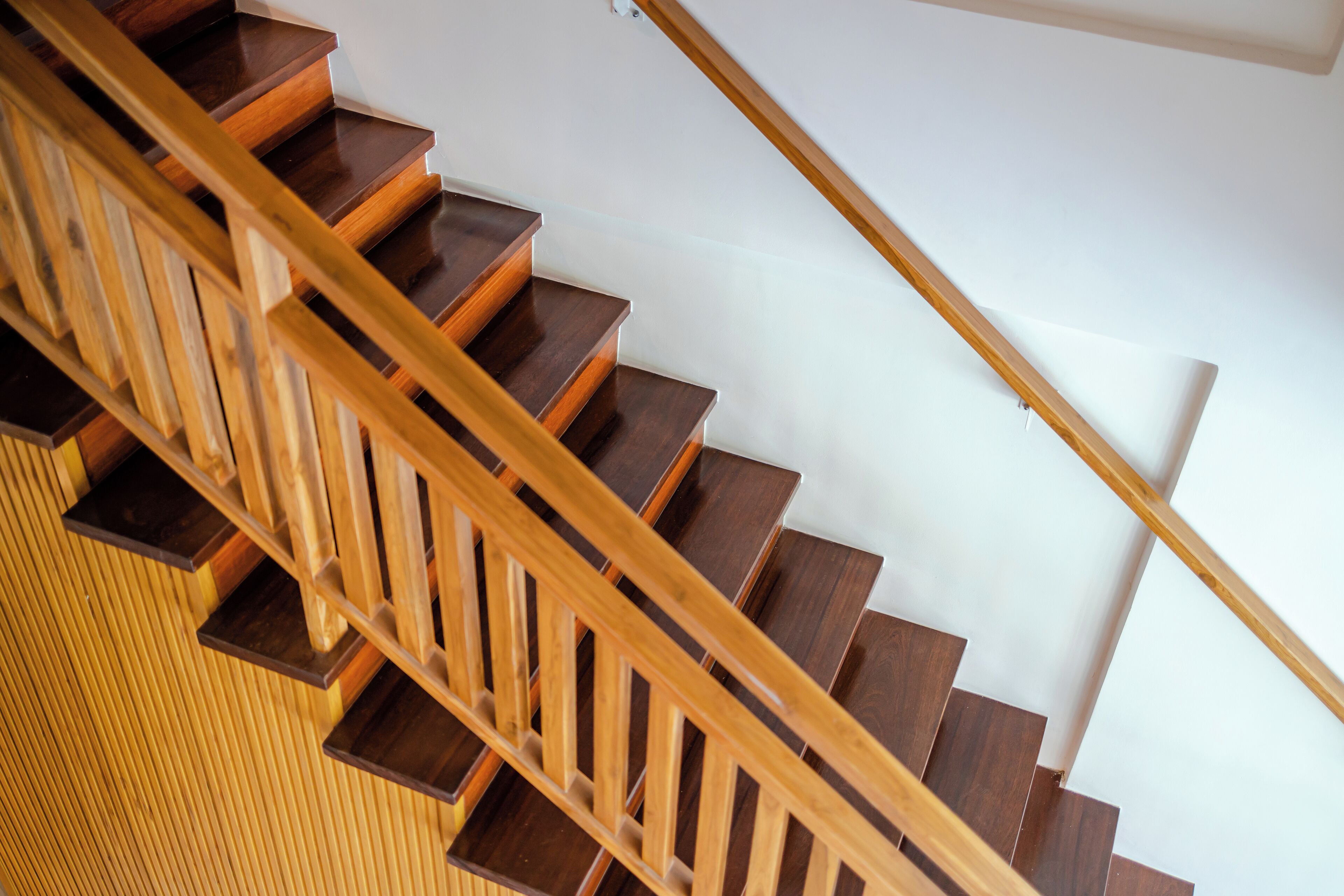 Een houten trap met een leuning, die uitkomt op een plateau.