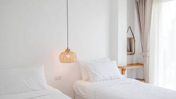 Quarto com duas camas, luminária pendente, prateleira de madeira e janela com cortinas.