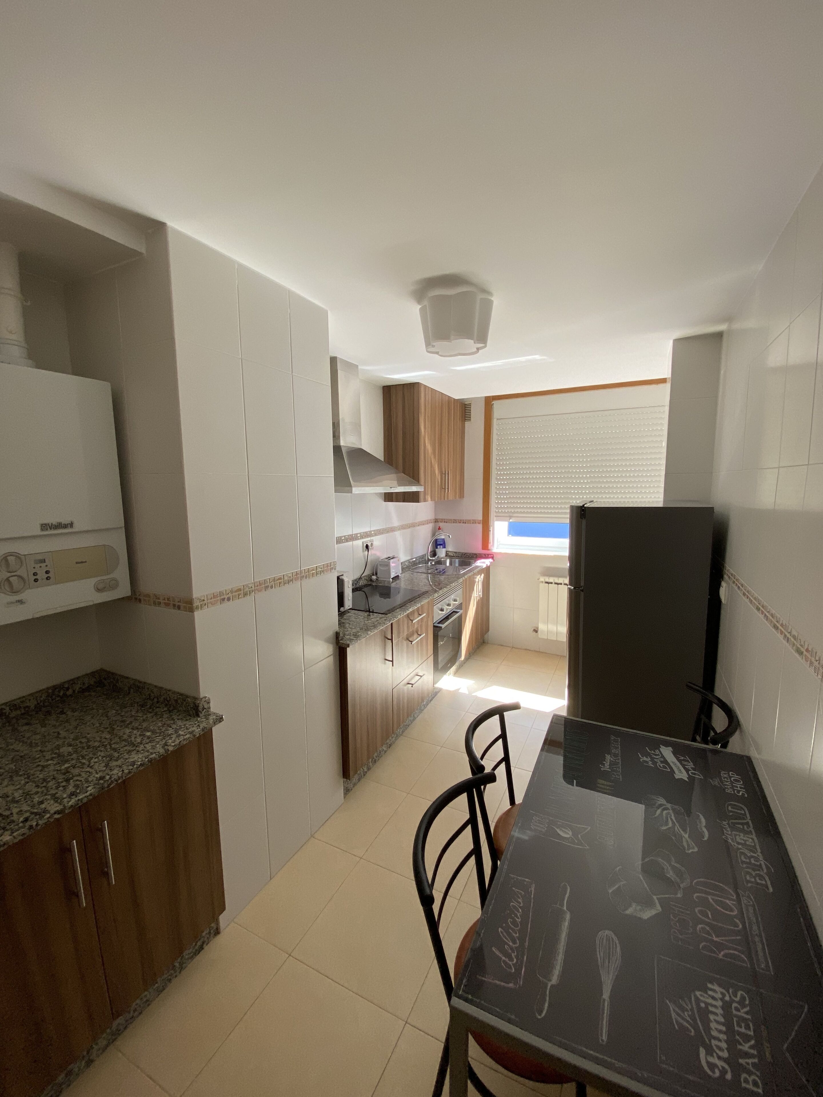 Una cocina compacta con una mesa de comedor, sillas y un refrigerador.