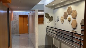 A modern hallway with a marble floor, wooden doors, and a wall with hexagonal stone art pieces. - dpCristal Calvo Sotelo 164 4C (Sarria)