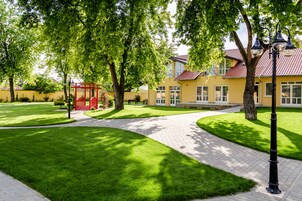 A well-maintained courtyard with a paved walkway, a red gazebo, and a yellow building with a red roof.