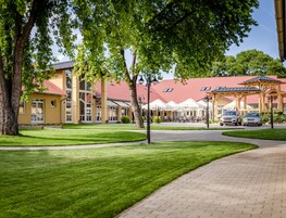 A hotel with outdoor seating, a red roof, and a paved walkway.