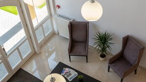 A spacious room with large windows, two chairs, a coffee table, and hanging pendant lights. - Budapest Airport Eprespark Hotel (Vecsés)