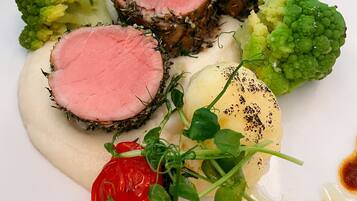 A plate of food with sliced meat, vegetables, and a sauce.