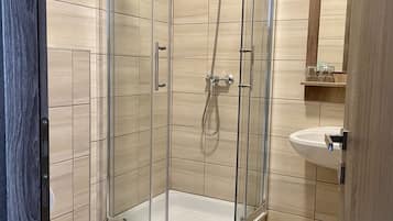 Un baño moderno con ducha de vidrio, inodoro y lavamanos.