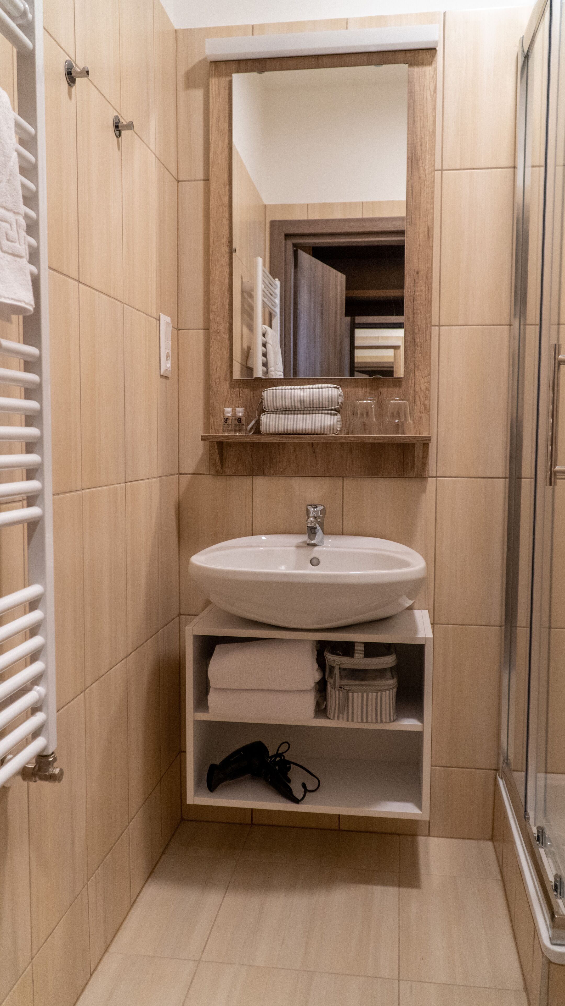 A bathroom with a wooden vanity, a sink, a mirror, and a shower.