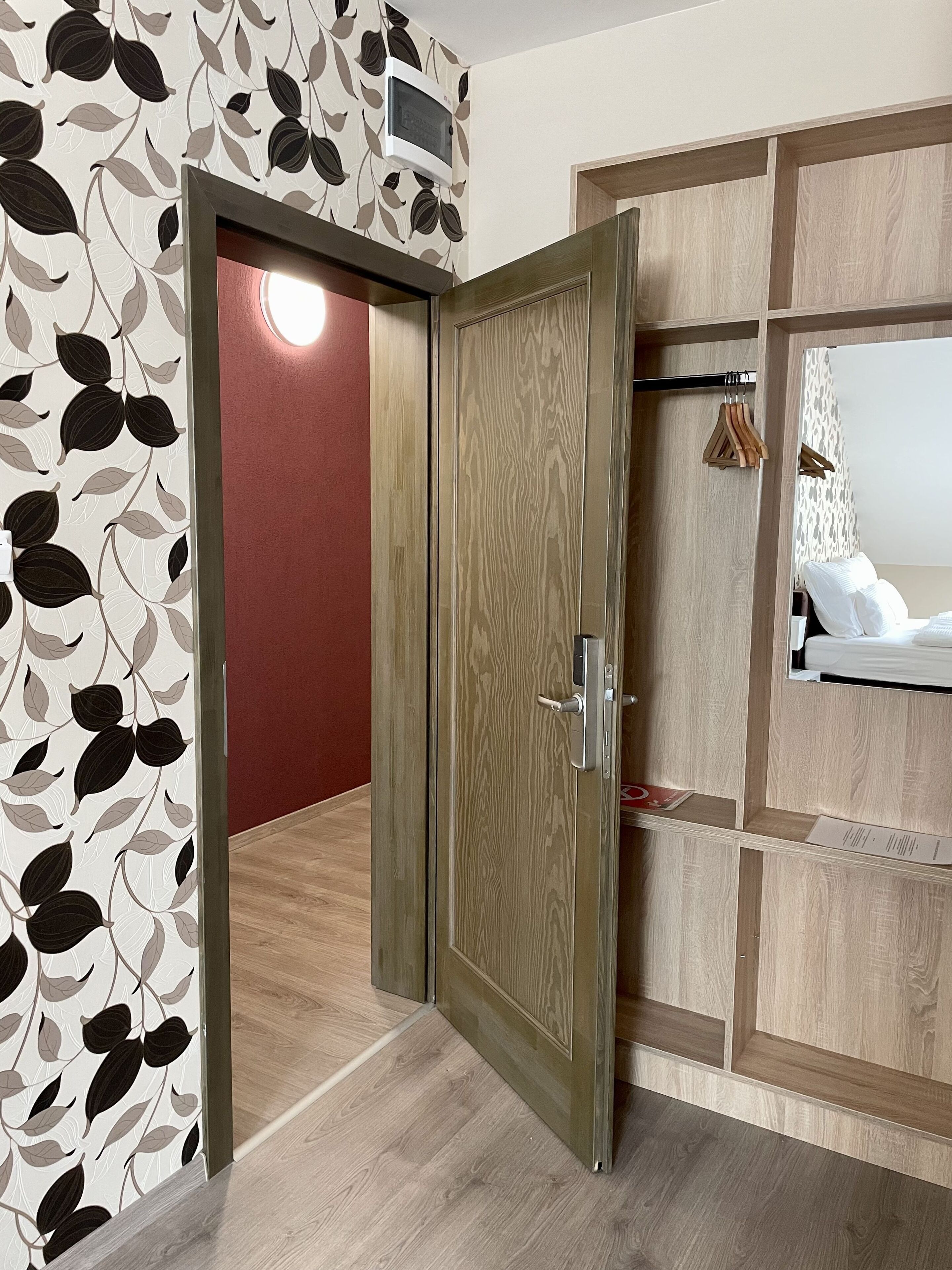 A room with a wooden wardrobe, a mirror, and a red wall.