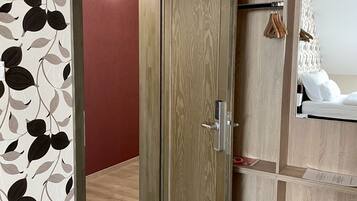 A room with a wooden wardrobe, a mirror, and a red wall.
